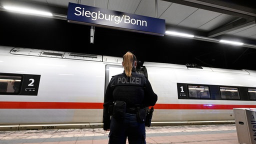 Eine Polizistin steht am Siegburger Bahnhof vor dem ICE, in dem sich der Vorfall ereignet hat