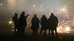 Menschengruppe steht vor Silvesterfeuerwerk