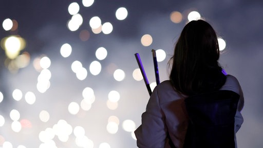 Eine Person schaut sich Silvester-Raketen an