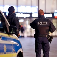 Zwei Polizisten stehen auf dem Bahnhofsvorplatz des Kölner Hauptbahnhofs. 