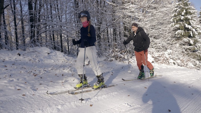 Zwei Personen wandern auf Ski den Berg hoch