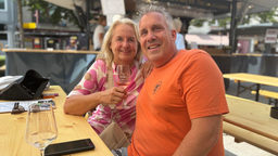 Astrid Beyer (links) hat ein Glas Wein in der Hand un sitzt neben ihrem Lebensgefährten (rechts)