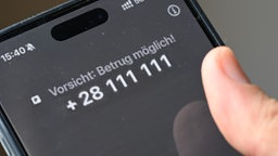 ein Smartphone auf dem der Warntext "Vorsicht: Betrug möglich!" zu lesen ist