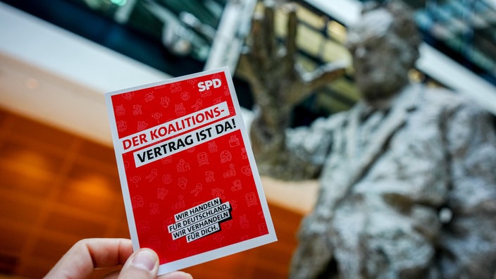 Flyer "Der Koalitionsvertrag ist da" vor Statue von Willy Brandt