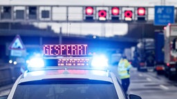 Auf einem Polizeifahrzeug leuchtet die Aufschrift "Gesperrt" vor einem Tunnel