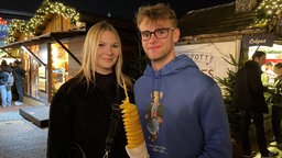 Eine Frau und ein Mann, der eine Spiralkartoffel in der Hand hält.