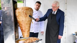 Bundespräsident Frank-Walter Steinmeier (rechts) schneidet unter Anleitung Döner.