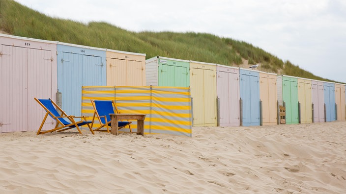 Bunte Strandcontainer in den Niederlanden mit zwei Strandliegen davor