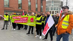 Streikende Mitarbeiter mit Schildern und Fahnen in der Hand
