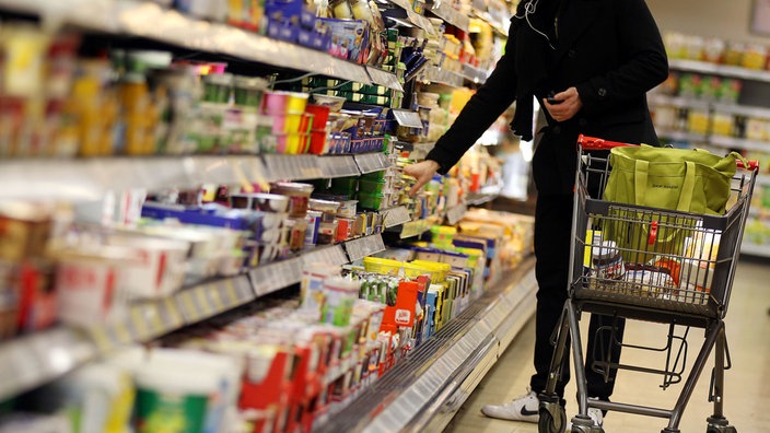 Eine Person greift in ein Kühlregal eines Supermarkts