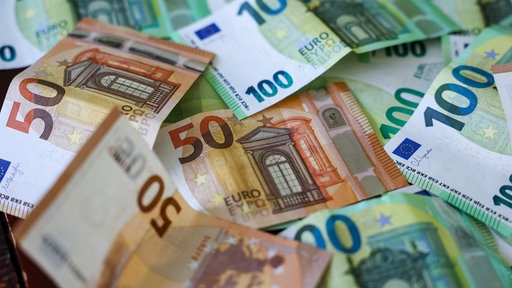 Mehrere Hunderter und Fünfziger Euro Geldscheine liegen auf einem Tisch