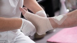 Eine Pflegefachkraft legt in der ambulanten Pflege einen Kompressionsverband an