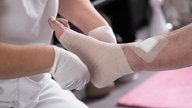 Eine Pflegefachkraft legt in der ambulanten Pflege einen Kompressionsverband an