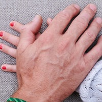 Eine Männerhand liegt auf einer Mädchenhand (gestellte Szene)