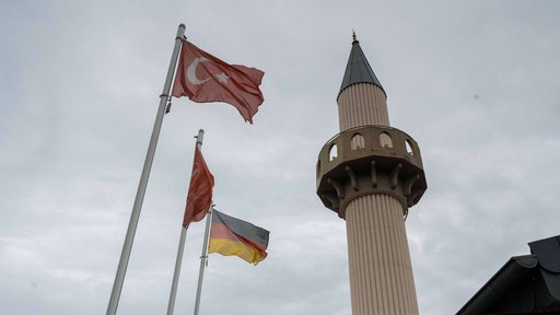 Eine Türkische und Deutsche Flagge weht neben einer Moschee 
