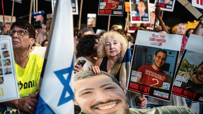 Menschen auf dem Geiselplatz in Tel Aviv halten Plakate