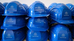 Schutzhelme mit dem Schriftzug «thyssenkrupp» liegen auf einem Tisch im Besucherzentrum «Oceanworld» auf der Werft von Thyssenkrupp Marine Systems (TKMS)