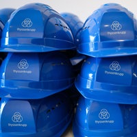 Schutzhelme mit dem Schriftzug «thyssenkrupp» liegen auf einem Tisch im Besucherzentrum «Oceanworld» auf der Werft von Thyssenkrupp Marine Systems (TKMS)