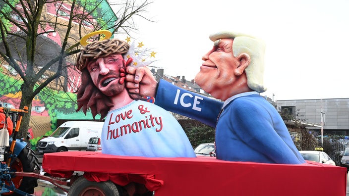 Ein Jesus mit Dornenkrone und Aufschrift "Love & humanity" wird von Trump geboxt. Auf Trumps Ärmel steht ICE