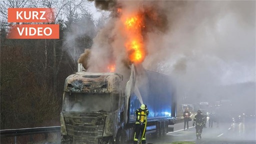 brennender LKW am Straßenrand, der von der Feuerwehr gelöscht wird 