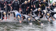 Teilnehmende des Bonner Triathlons springen in den Rhein.