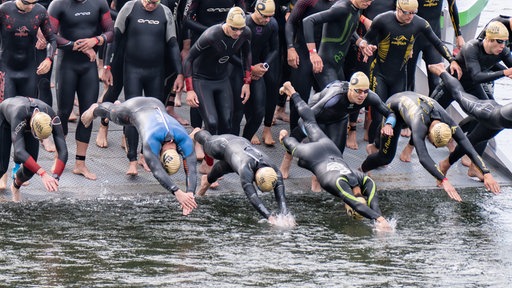 Teilnehmende des Bonner Triathlons springen in den Rhein.