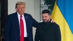 Präsident Trump hat seine Hand auf der Schulter von Präsident Selenskyj 