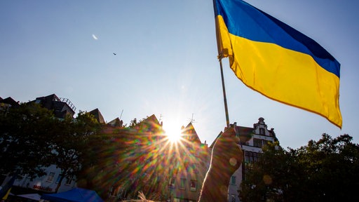 Eine Hand hält die Flagge der Ukraine hoch