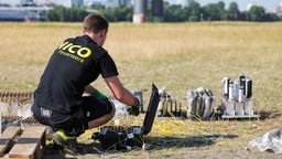 Ein Mitarbeiter der Feuerwerksfirma arbeitet am Unfallort auf den Rheinwiesen.