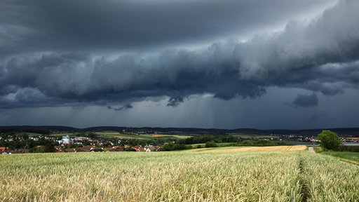 Eine Gewitterzelle mit dunklen Wolken baut sich am Himmel auf