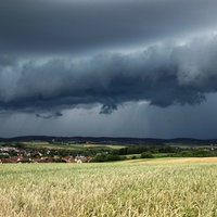 Eine Gewitterzelle mit dunklen Wolken baut sich am Himmel auf