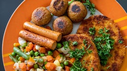 Vegane Falafel, vegane Schnitzel, vegane Würstchen und Gemüse sind auf einem Teller