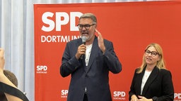 Der amtierende Dortmunder Oberbürgermeister Thomas Westphal steht vor einem roten Hintergrund mit SPD-Aufschrift und spricht in ein Mikrofon.