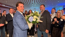 Das Bild zeigt Alexander Biber mit einem Blumenstrauß.