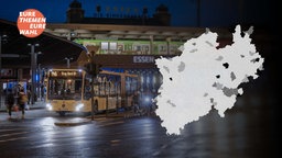 Ein Linienbus steht nachts an einer Bushaltestelle, im Vordergrung eine Karte mit den Gemeinde-Umrissen von NRW
