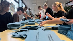 Blaue Wahlbriefe werden von den Wahlhelfern ausgezählt 