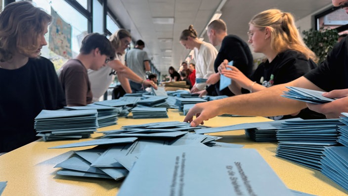 Blaue Wahlbriefe werden von den Wahlhelfern ausgezählt 