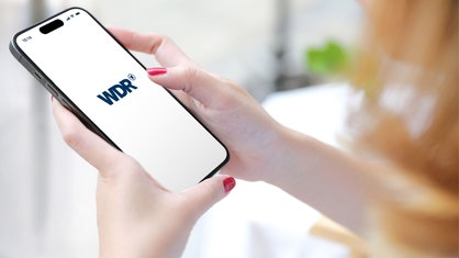 Eine Frau hat auf einem Smartphone die WDR aktuell App geöffnet.