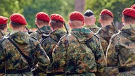 Eine Gruppe Soldaten in Uniform steht in Formation mit Gewehren bewaffnet