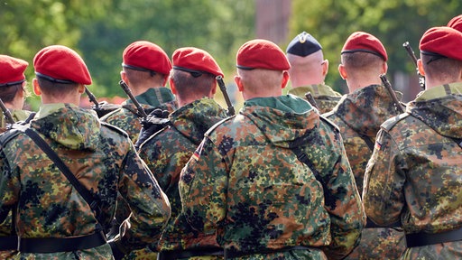 Eine Gruppe Soldaten in Uniform steht in Formation mit Gewehren bewaffnet