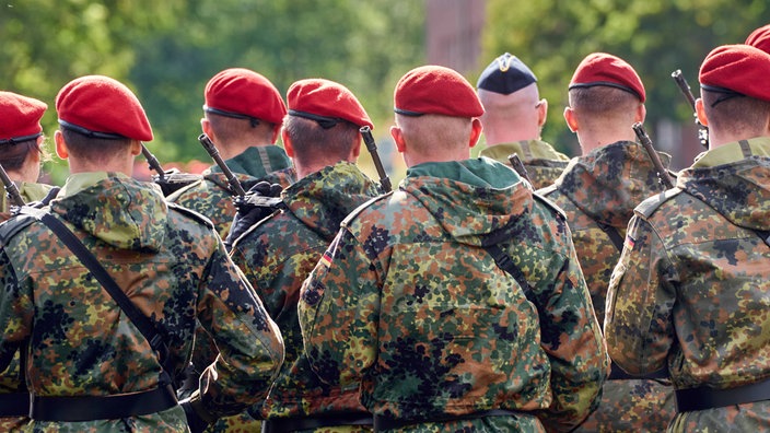 Eine Gruppe Soldaten in Uniform steht in Formation mit Gewehren bewaffnet