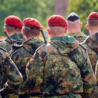 Eine Gruppe Soldaten in Uniform steht in Formation mit Gewehren bewaffnet