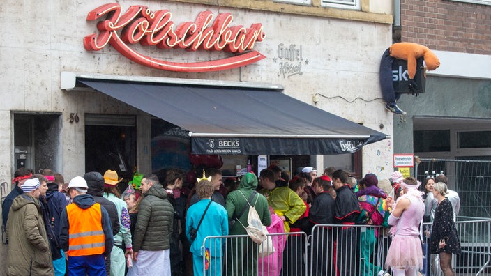 Schlange vor einer vollen Kneipe in Köln am Weiberfastnacht 
