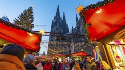 Menschen spazieren über den Weihnachtsmarkt neben dem Kölner Dom