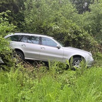 Ein silberner Mercedes liegt mit Totalschaden im Graben. 