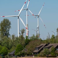 Hinter einer Wohnsiedlung ragen Windräder empor