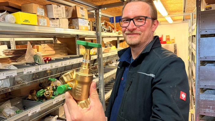 Firmenchef Michael Friedrich steht mit einem Ersatzteil in seinem Ersatzteillager