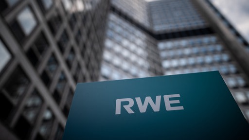 Schild mit der Aufschrift "RWE" vor einem modernen Hochhaus mit Glasfassade im Hintergrund.