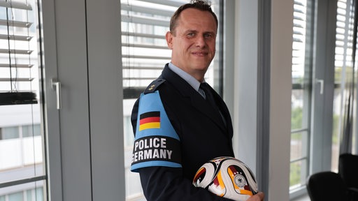 Mika Stalleicken posiert in Uniform mit einem Fußball in der Hand.