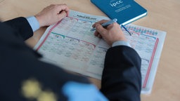 Mika Stalleicken sitzt vor einem Tunierbaum der WM aus Papier und kreuzt etwas an.